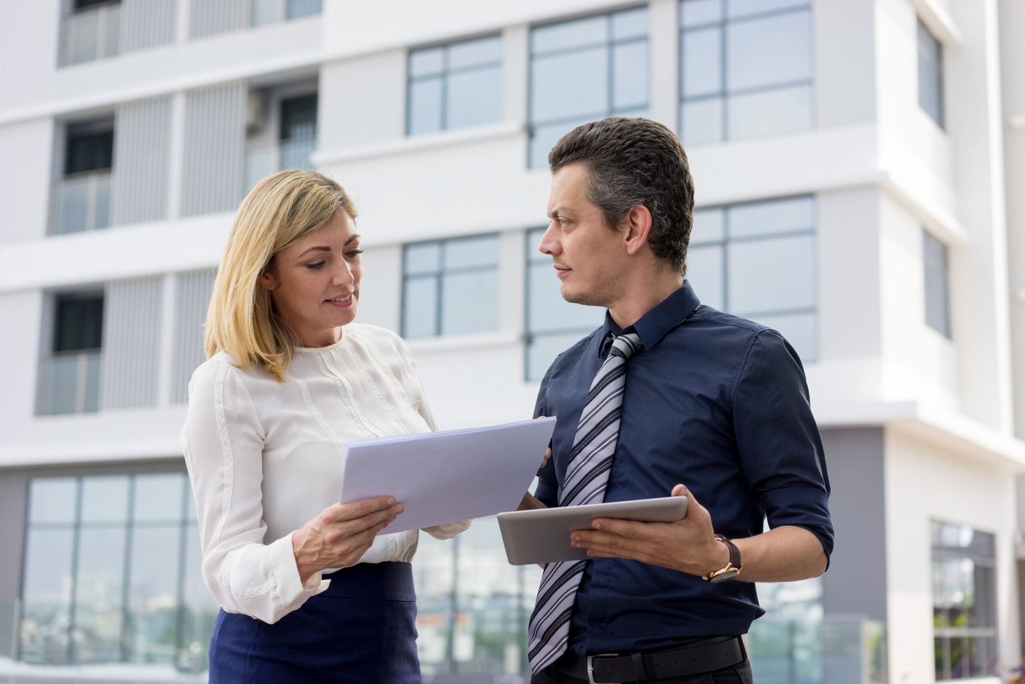 content-business-partners-discussing-documents-outdoors-scaled